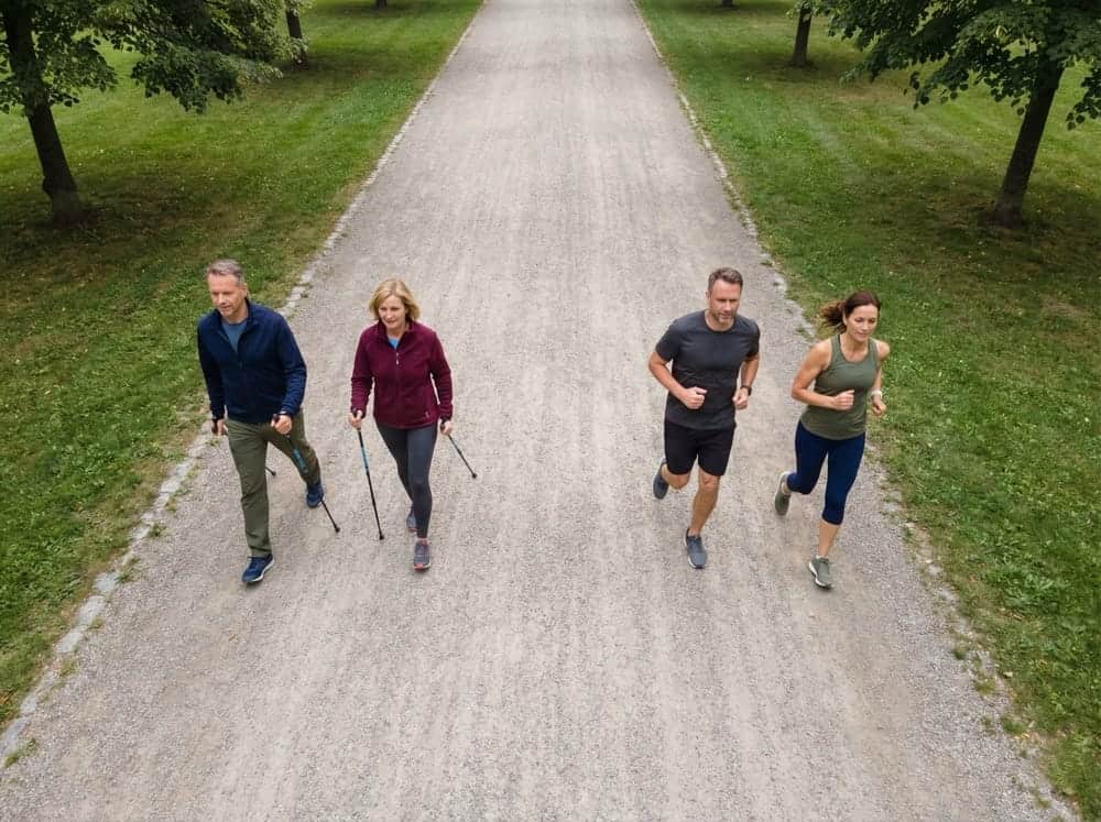 Laufen und Walking bei Migräne 2 Vogelperspektive auf Parkweg mit zwei Walkern und zwei Läufern gleichzeitig bei natürlichem Tageslicht