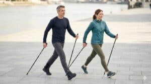 Mann und Frau beim Nordic Walking mit korrekter Technik auf einer Uferpromenade